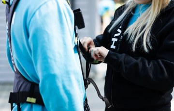 Opiskelija kiinnittää turvavaljaita asiakkaalle