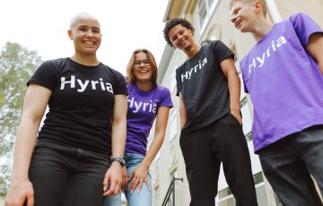 ryhma nuoria seisoo kameraan päin. Heidän paidoissaan on Hyrian logot.