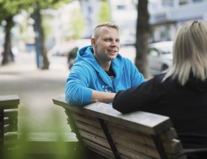 Henkilöt juttelevat puistonpenkillä
