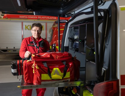 Henkilö esittelee ambulanssin tarvikelaukkua ajoneuvohallissa.